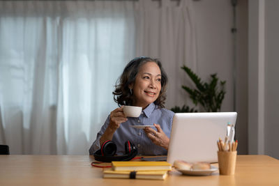 Portrait of young woman using mobile phone while sitting at home