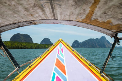 Longtail wooden boat sail on ocean in phang nga bay with green island and mangrove forest, thailand.