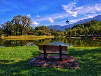 Bench by lake against sky