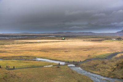 Scenic view of landscape and river against cloudy sky