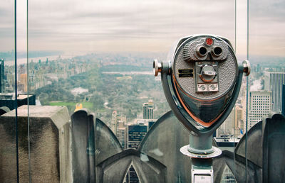 Close-up of coin-operated binoculars against buildings in city