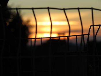 Close-up of silhouette fence during sunset
