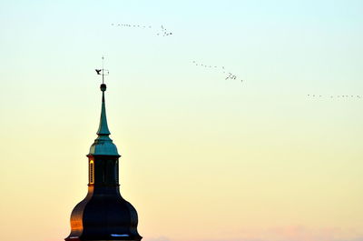 Low angle view of birds flying over built structure