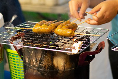 Midsection of person preparing food on barbecue grill