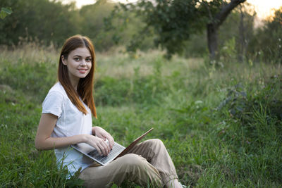 Portrait of young woman sitting on field