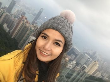 Portrait of happy woman wearing knit hat against victoria harbour