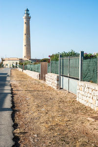 Lighthouse amidst buildings against clear sky