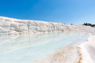 Scenic view of snow covered land against clear blue sky