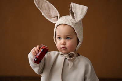 Portrait of cute boy holding baby against gray background