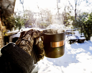 Close-up of gloved hand holding hot tea cup