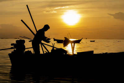 Silhouette man standing by sea against sky during sunset