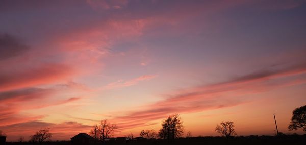 Low angle view of silhouette trees against dramatic sky