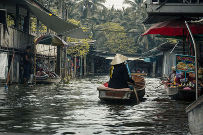Rear view of man rowing boat in canal