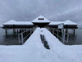 Gazebo by building against sky during winter