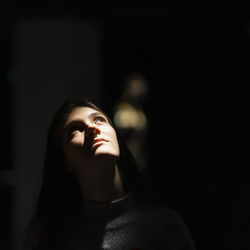 Close-up of woman looking up in dark room