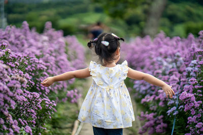 Rear view of woman standing on purple flowering plants