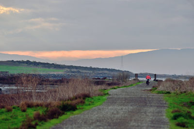 Rear view of man on road against sky during sunset