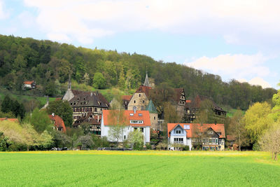 Houses on green landscape against sky