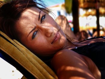 Close-up portrait of beautiful young woman relaxing on deck chair at beach