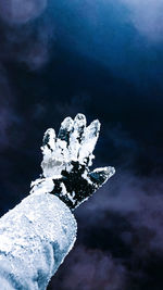 Close-up of hand holding ice cream against sky