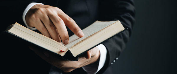 Close-up of hand holding book against gray background