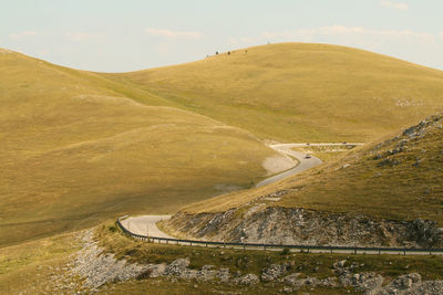 Scenic view of road by mountains against sky