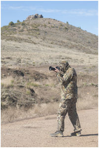 Side view of army soldier photographing with camera on field