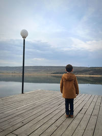 Rear view of man standing at beach against sky