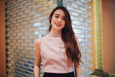 Portrait of beautiful woman standing against glass wall