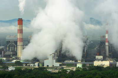 Smoke emitting from factory against sky