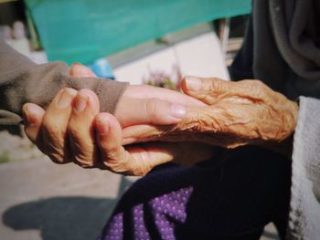 Midsection of senior woman holding grandchild hand outdoors