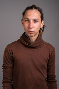 Portrait of young man standing against gray background