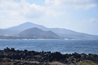 Scenic view of sea and mountains against sky