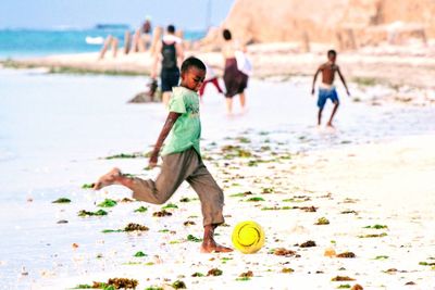 Side view of boy playing with ball on beach