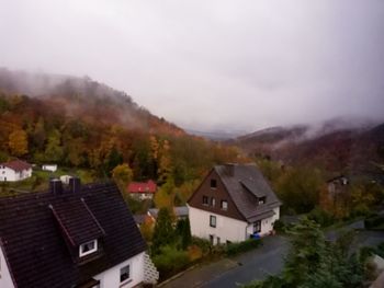 Houses by buildings against sky