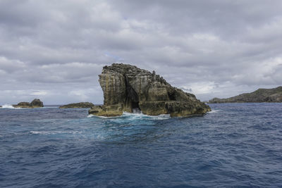 Rock formation in sea against sky