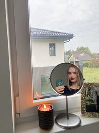 Portrait of woman standing by glass window