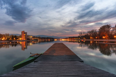 Empty jetty in lake against sky during sunset