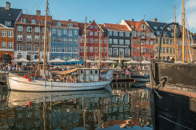 Sailboats moored on canal by buildings in city against sky