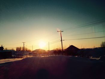 Snow covered road against sky during sunset