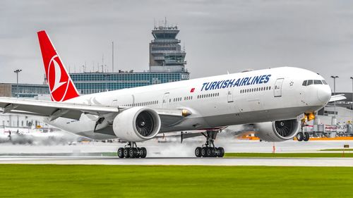 Airplane flying over airport runway against sky