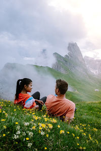 Rear view of friends sitting on land against sky