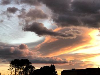 Low angle view of silhouette trees against dramatic sky