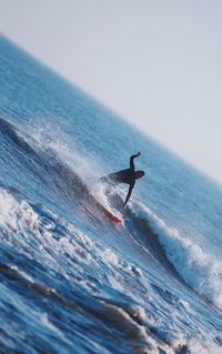 Man surfing in sea against sky