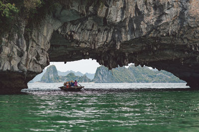 People rowing boat on halong bay under rock formation