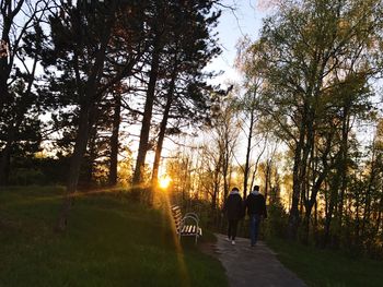 Rear view of silhouette people walking on landscape against sky during sunset