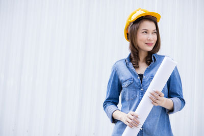 Portrait of smiling woman standing against wall