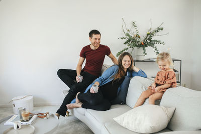 Full length of happy friends sitting on sofa