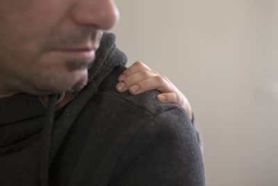 Close-up child hand on man shoulder against wall