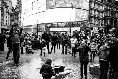 People watching street performer on road in city